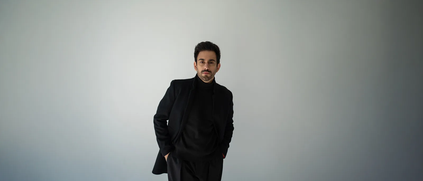 Bilal Khan in a black jacket against a quiet studio backdrop
