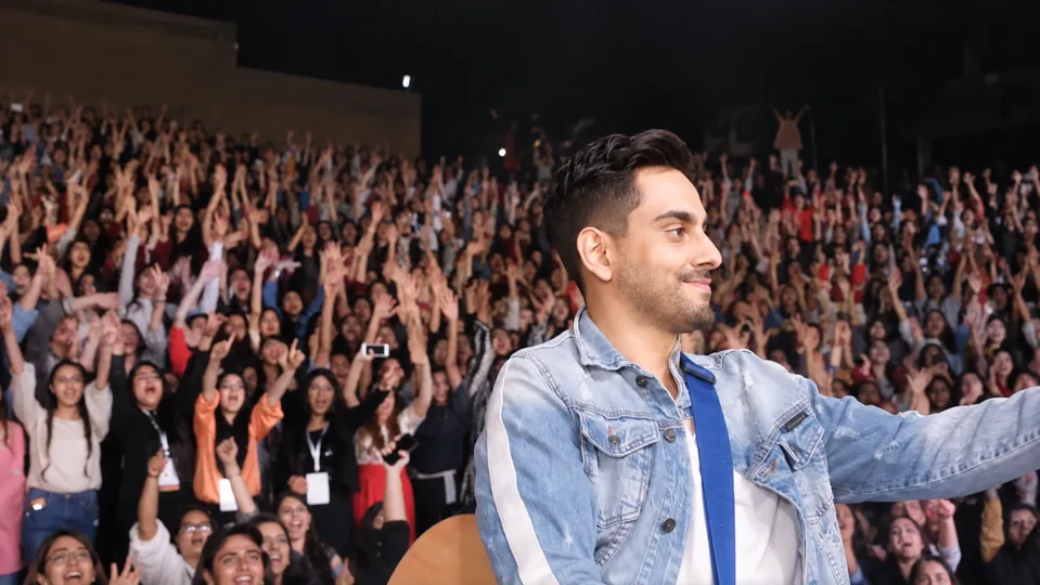 Bilal Khan facing a cheering audience, with hands raised across the crowd